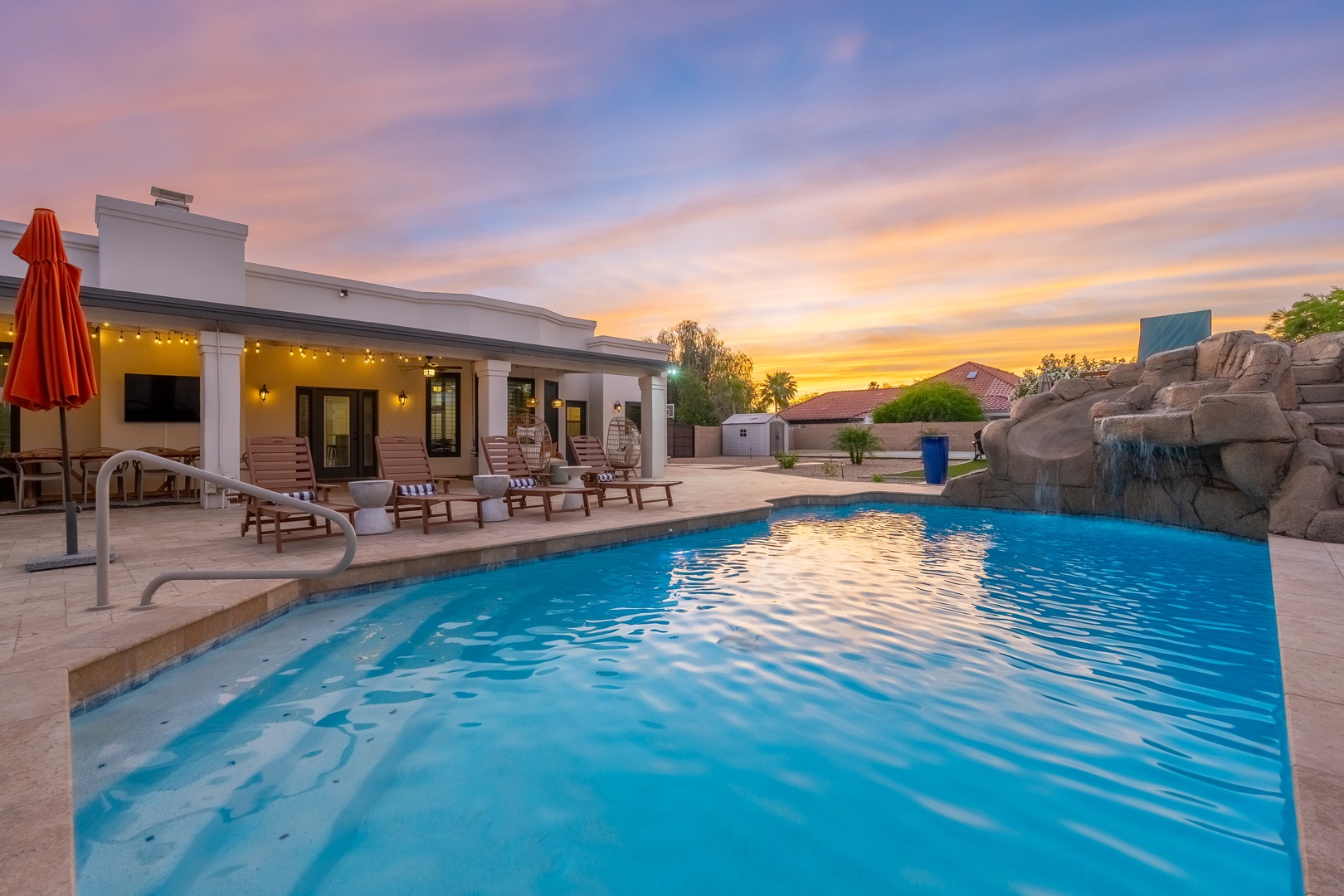 Stunning desert sky backdrop for your private pool retreat, complete with rock waterfall, sundeck, and covered patio with lounge seating.