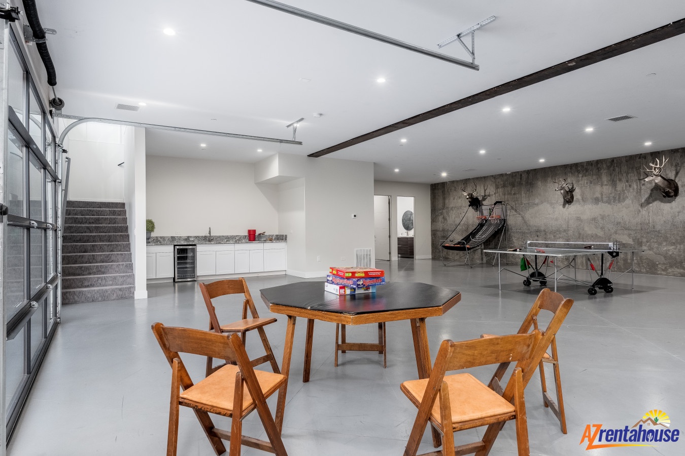 Relax in this sleek game room featuring ping pong, foosball, and board games, plus a modern kitchen for snacks during friendly competitions.