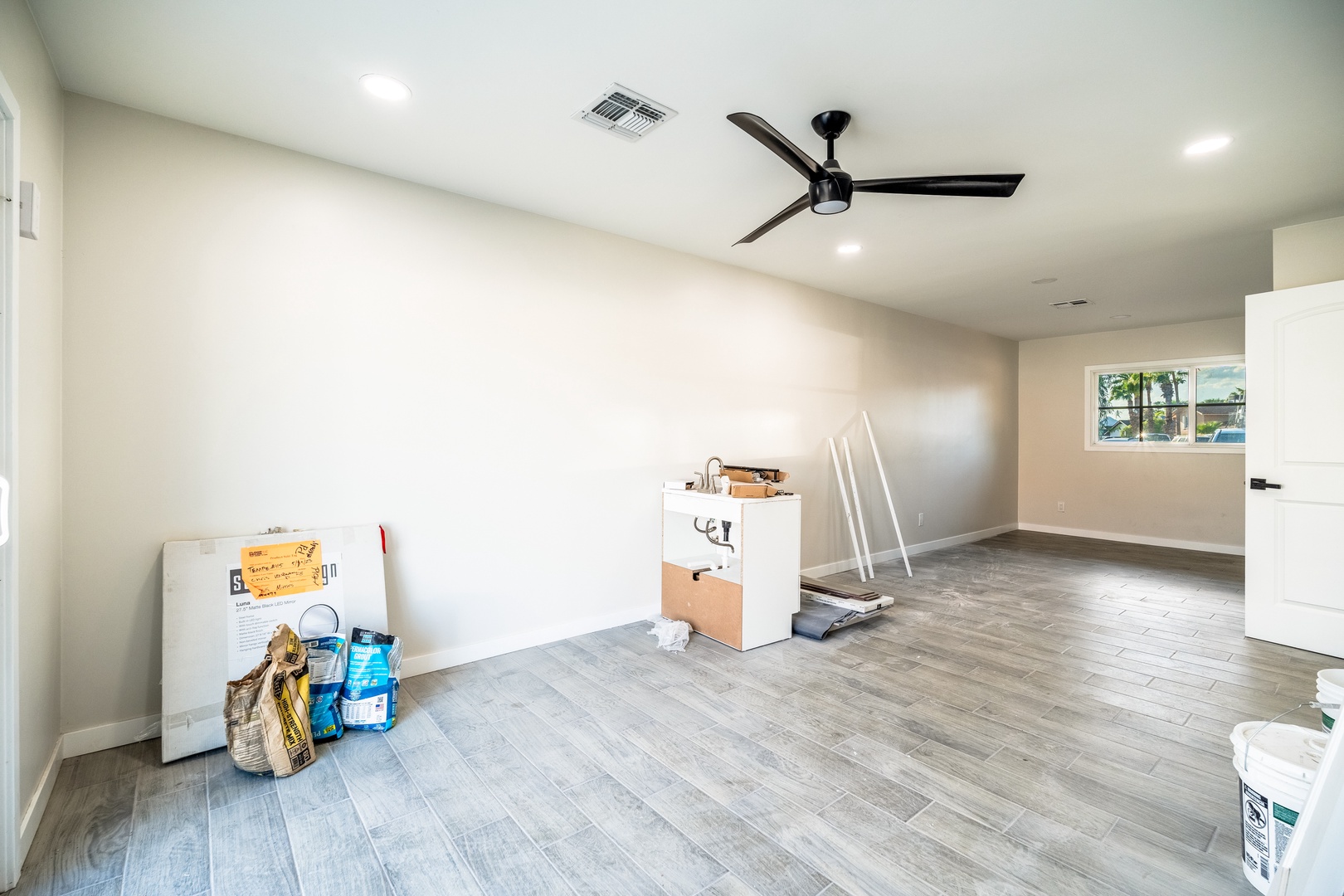 A bright, open-concept living area featuring modern flooring, recessed lighting, and a ceiling fan to keep you comfortable year-round. Natural light fills the space, ready for you to make it your own.