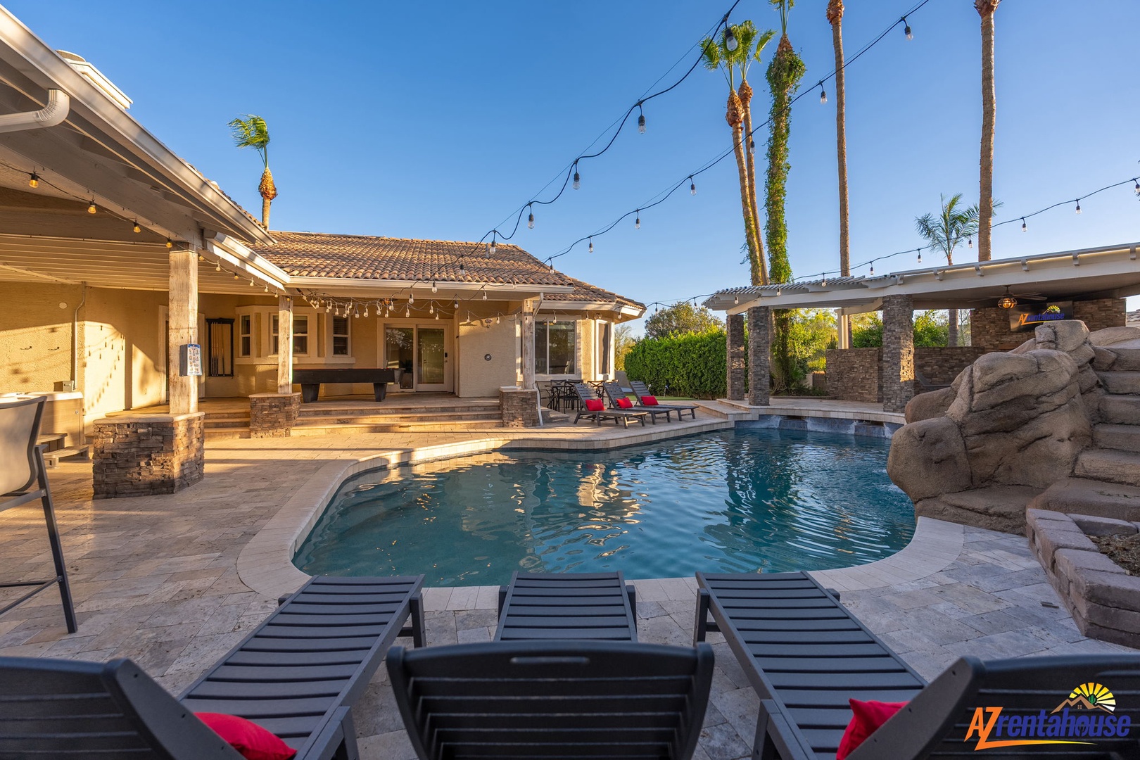 Sparkling pool framed by towering palms and festive string lights. Your private desert oasis awaits, with loungers perfectly positioned for soaking up the Arizona sun and unwinding poolside.
