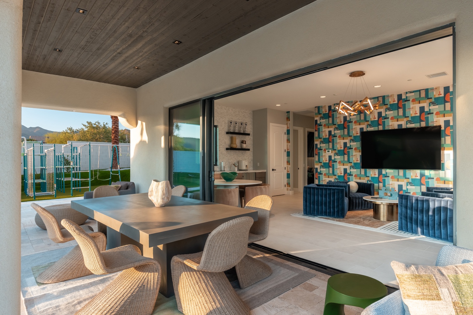 Your indoor-outdoor oasis awaits, where modern dining flows seamlessly into a vibrant entertainment space with mountain views just beyond. Perfect for gathering around the table or relaxing in style.