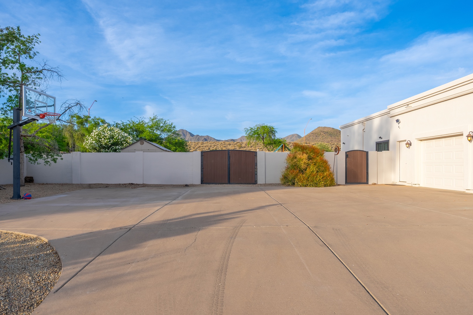 Spacious private driveway with basketball hoop and stunning desert mountain views, offering ample parking and room for outdoor fun under clear blue skies.
