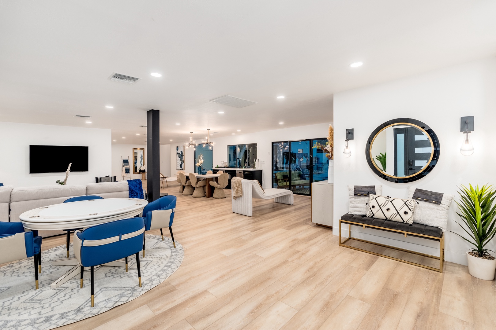 Step into a bright, open-concept living space where your vacation unfolds in style. Sunlight streams across pale wood floors, inviting you to relax on plush seating, gather around the dining table, or unwind in front of the sleek TV.