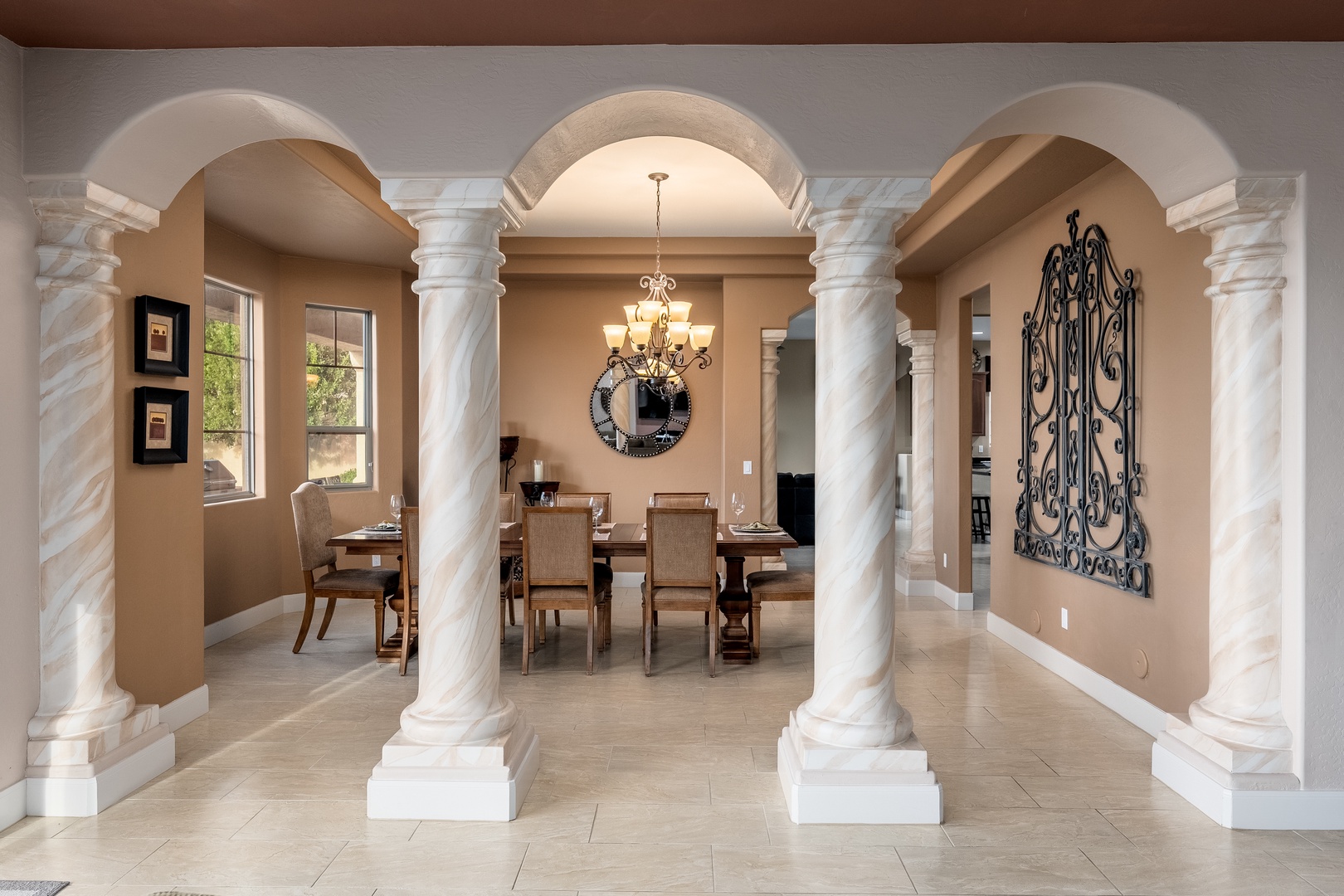 Step into an elegant dining space framed by graceful arches and marble columns. Warm lighting from the chandelier sets a welcoming tone as you gather around the table for memorable meals.