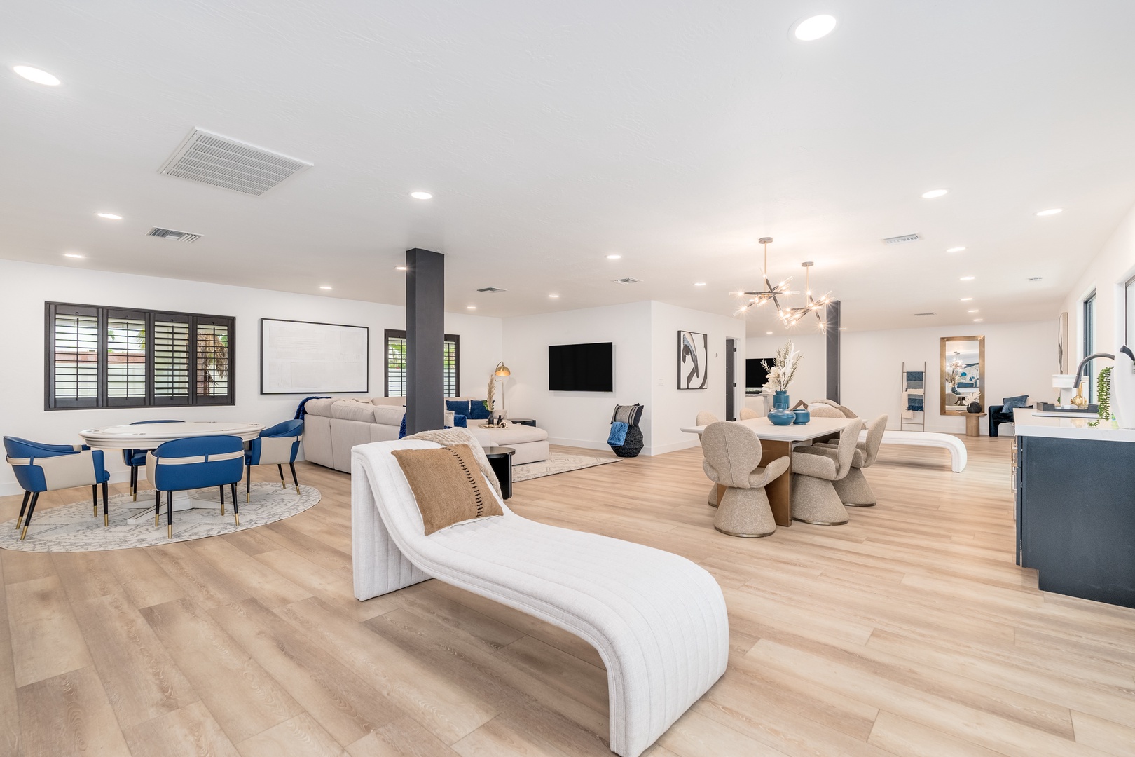 Step into your spacious open-concept living area where natural light fills the room through elegant shuttered windows. Gather around the dining table, relax on the plush sectional, or unwind on the modern chaise—your perfect retreat awaits.