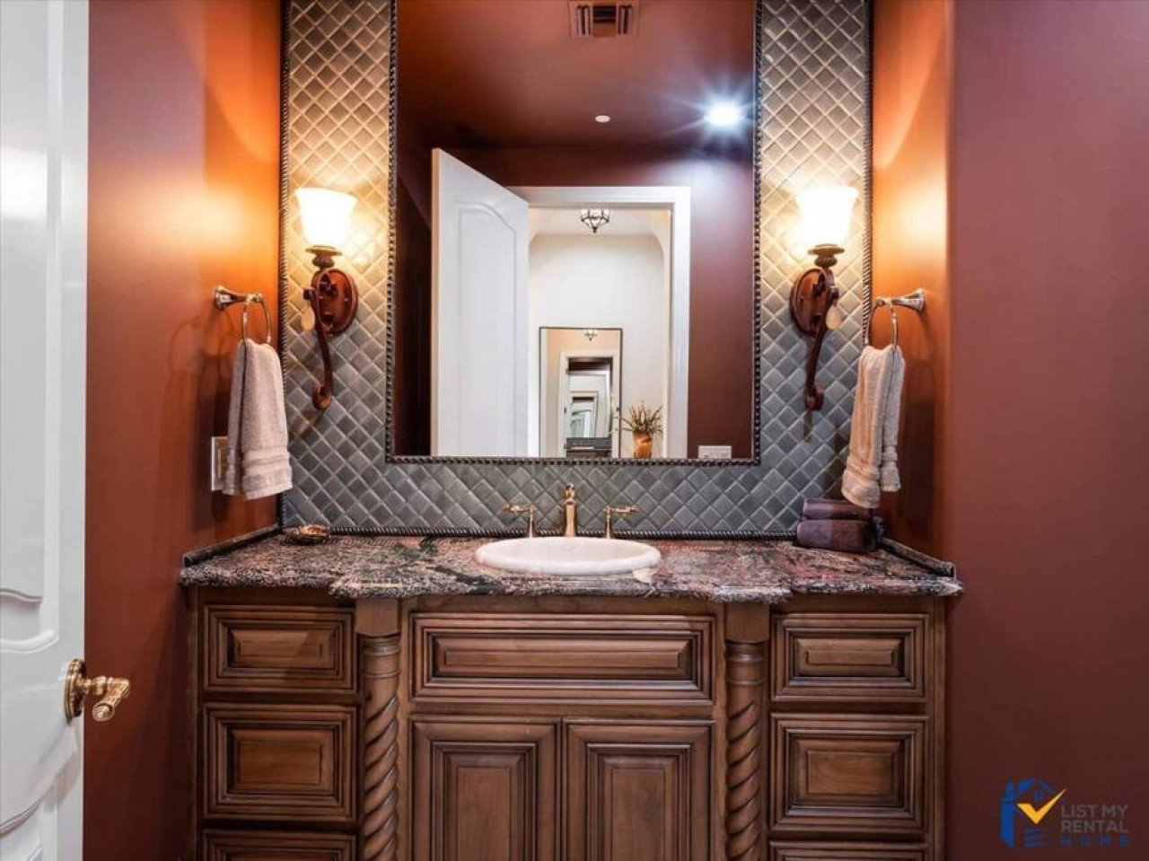 Pamper yourself in this luxurious vanity with granite countertops, elegant sconces, and rich wood cabinetry that makes your morning routine feel indulgent.