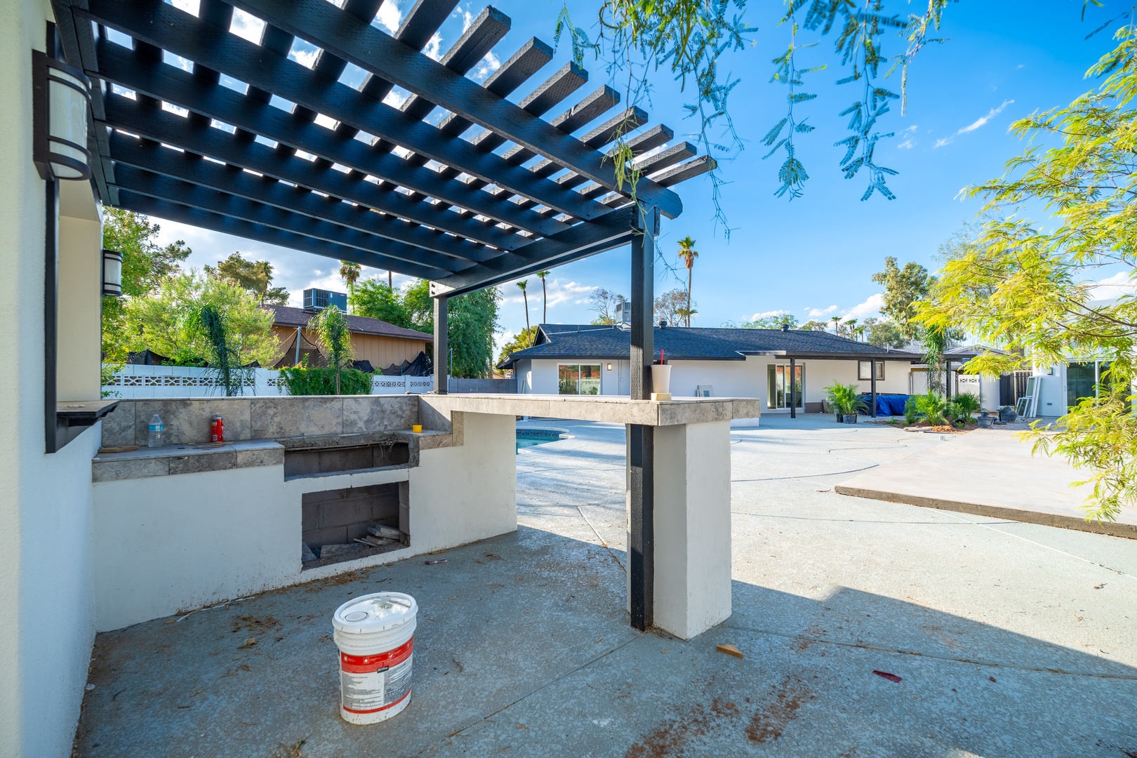 Your private outdoor kitchen and entertaining space awaits, complete with built-in BBQ counter and shaded pergola, opening to a spacious backyard with pool and multiple lounge areas perfect for sunny afternoons.