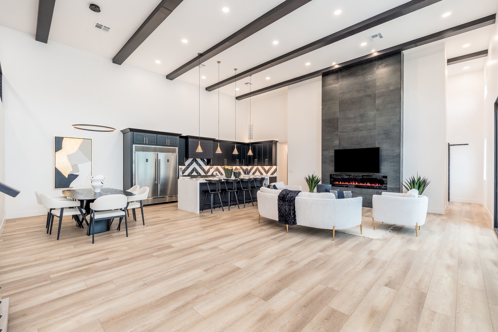 Sink into the plush seating and let the soft glow of the fireplace wrap you in warmth while you enjoy movie nights in this stunning open-concept living space with soaring ceilings.