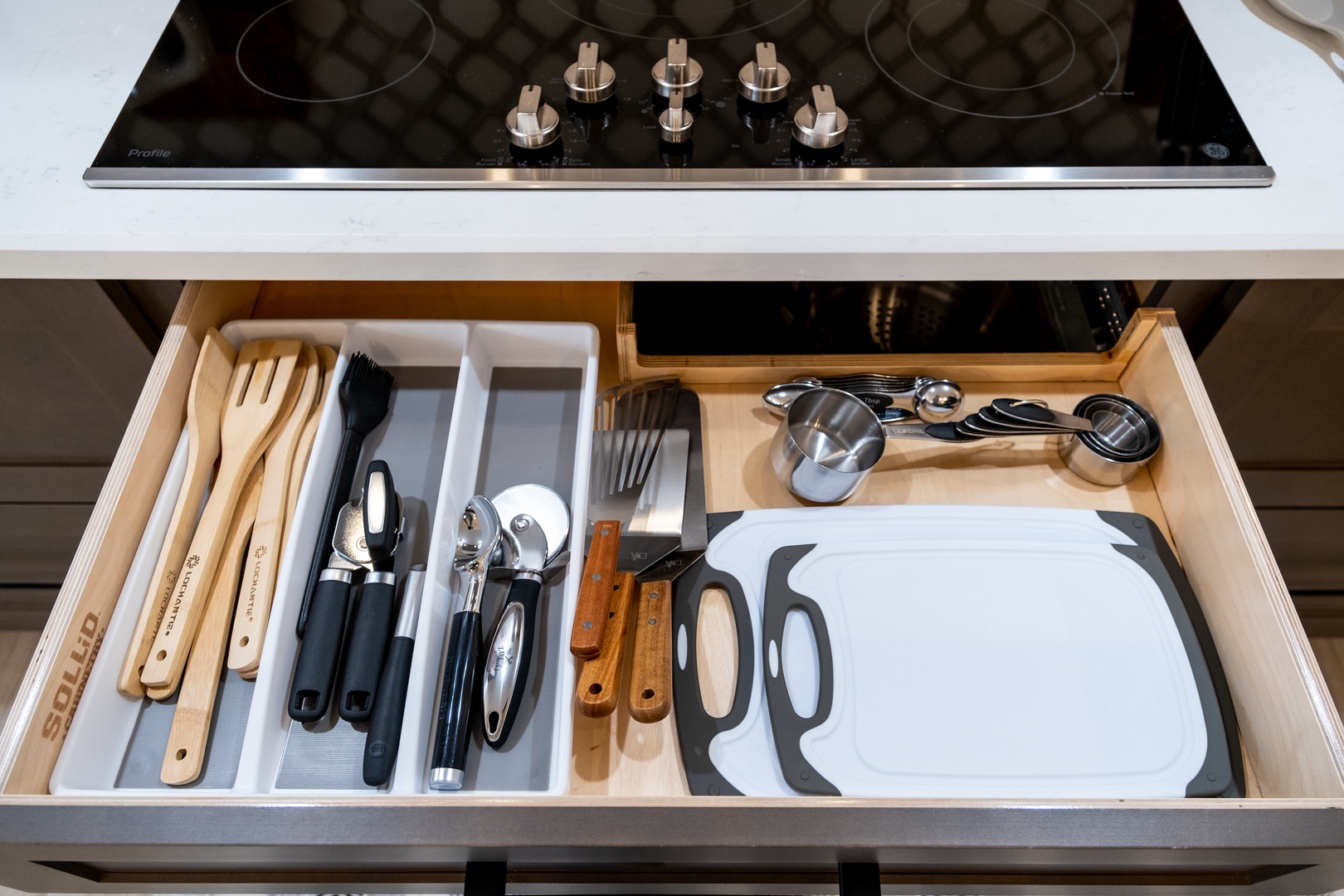 Your culinary adventures begin here, with a sleek induction cooktop and thoughtfully organized drawer stocked with quality utensils, cutting boards, and measuring cups—everything you need to cook with ease.