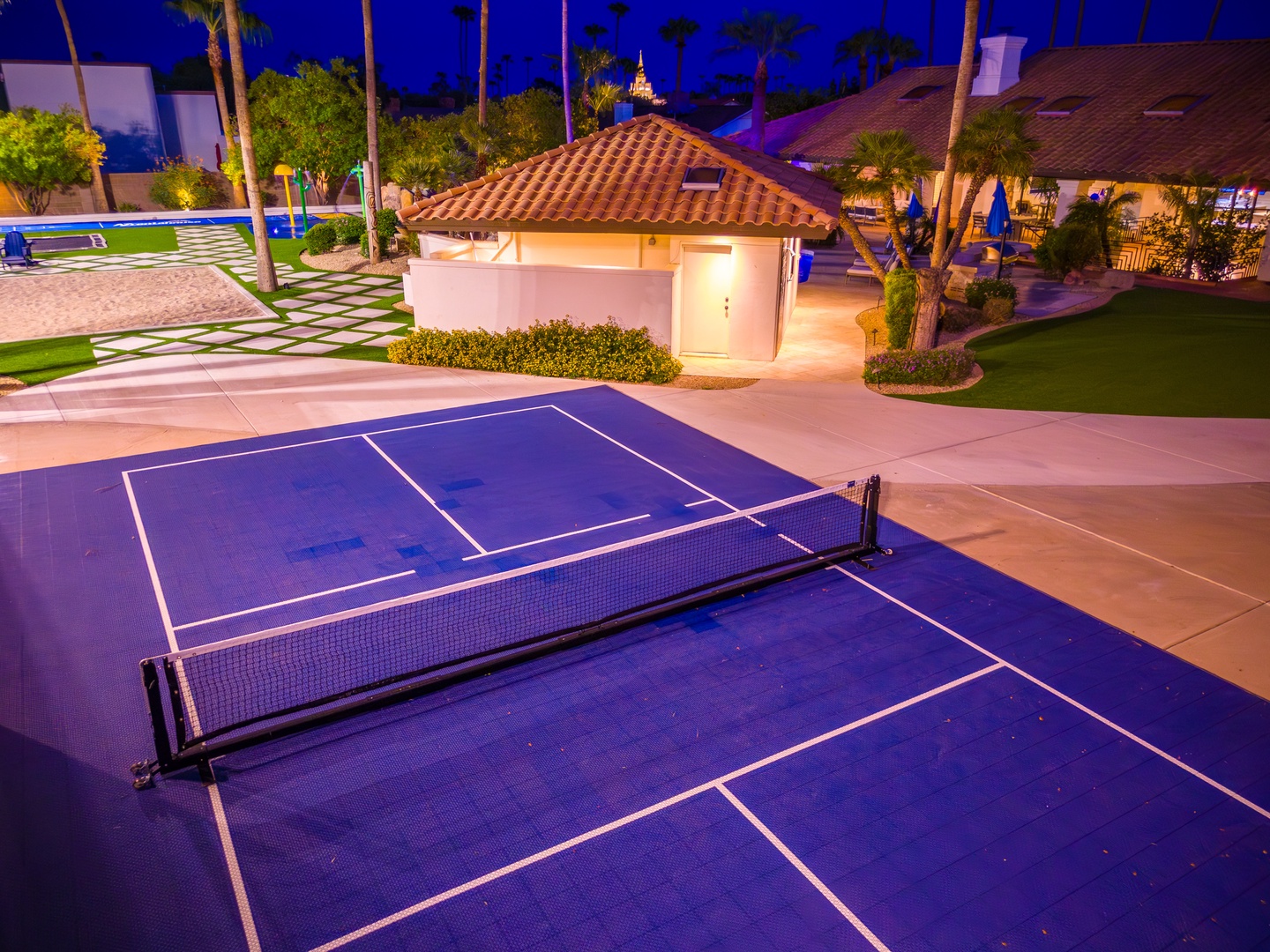 A private tennis court awaits beneath stunning evening skies, surrounded by lush palms and manicured grounds—an invitation for friendly matches and active escapes.