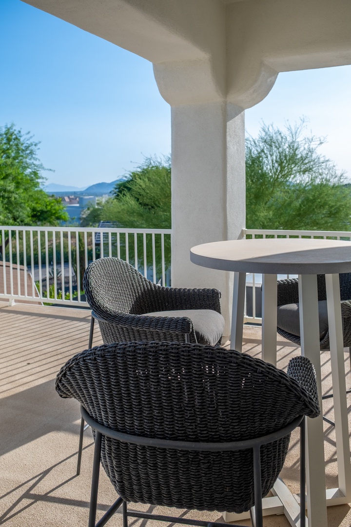 A covered balcony with contemporary seating offers views of the surrounding hills and neighborhood, perfect for morning coffee or evening relaxation in a peaceful desert setting.