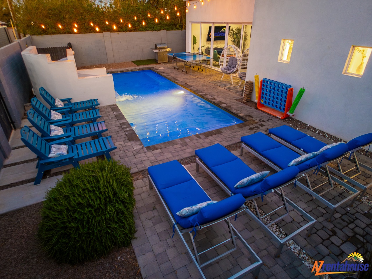 Your private backyard oasis awaits with sparkling pool, loungers, BBQ area, and twinkling string lights creating perfect evening ambiance.
