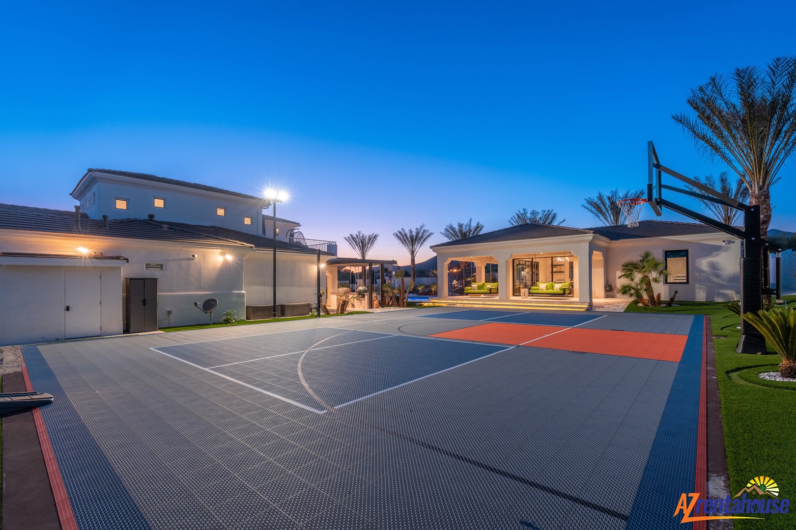 Luxury estate with full-size basketball court and tropical palms, perfect for active getaways at twilight.
