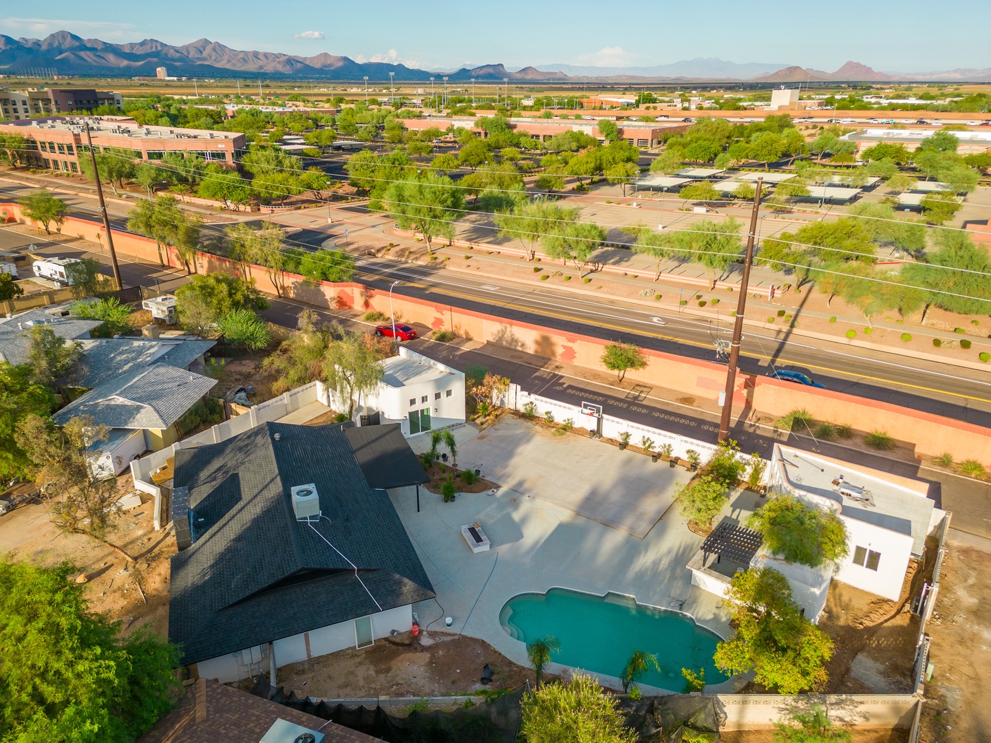 Aerial view showcasing the property's inviting pool and spacious grounds, set against a stunning desert landscape with majestic mountain vistas in the distance.