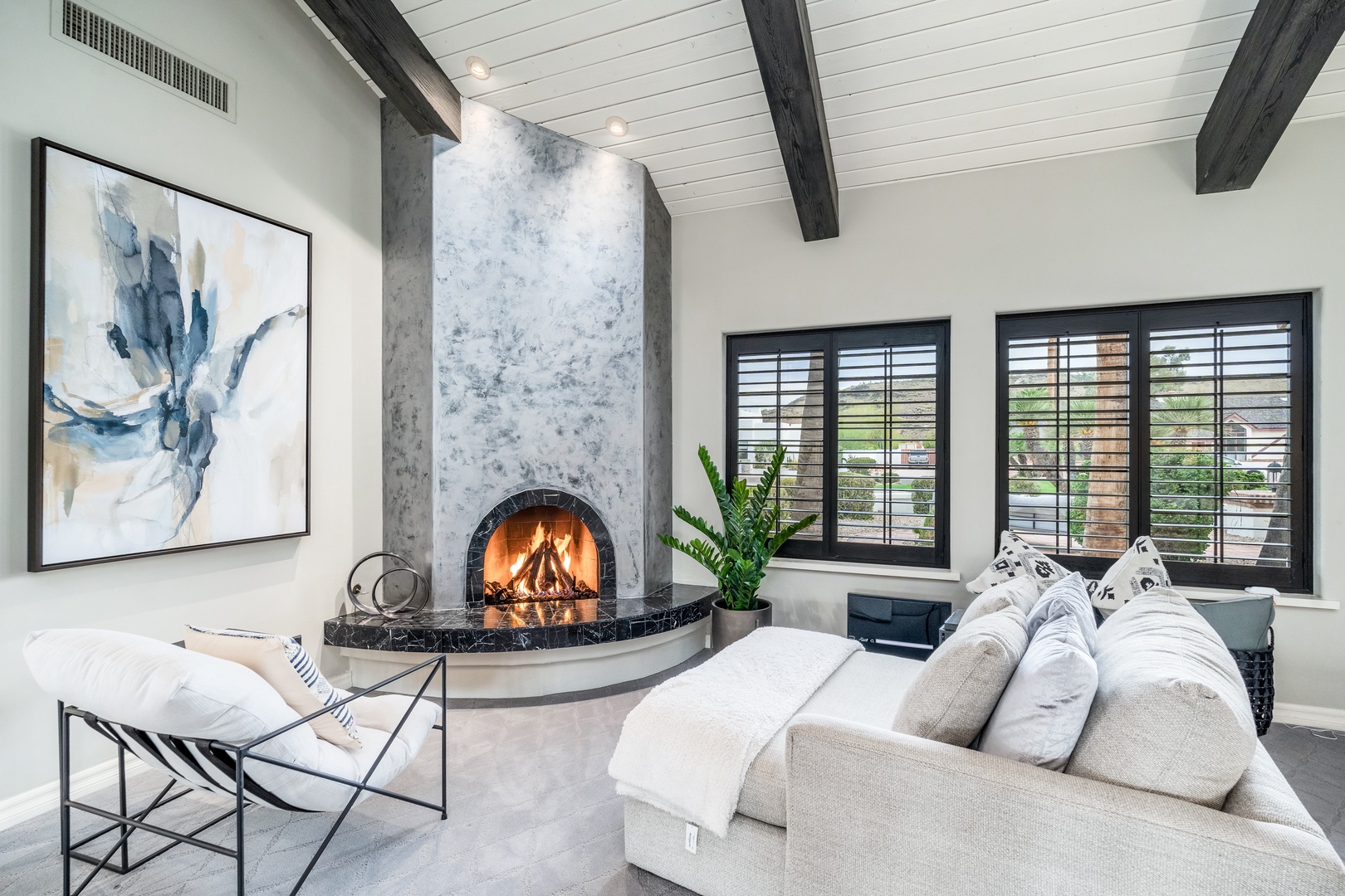 Sink into plush seating by the glowing fireplace, where dramatic beams and elegant artwork create your perfect retreat for cozy evenings in.