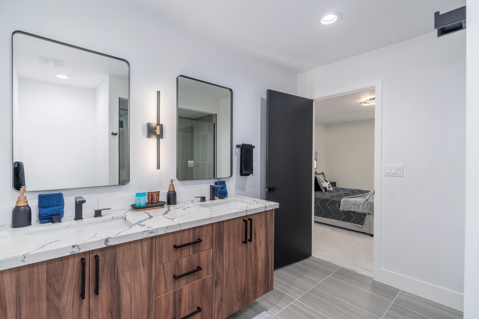 Your private bathroom features a stunning double vanity with marble countertops, modern fixtures, and warm wood cabinetry that creates a spa-like retreat for your morning routine.