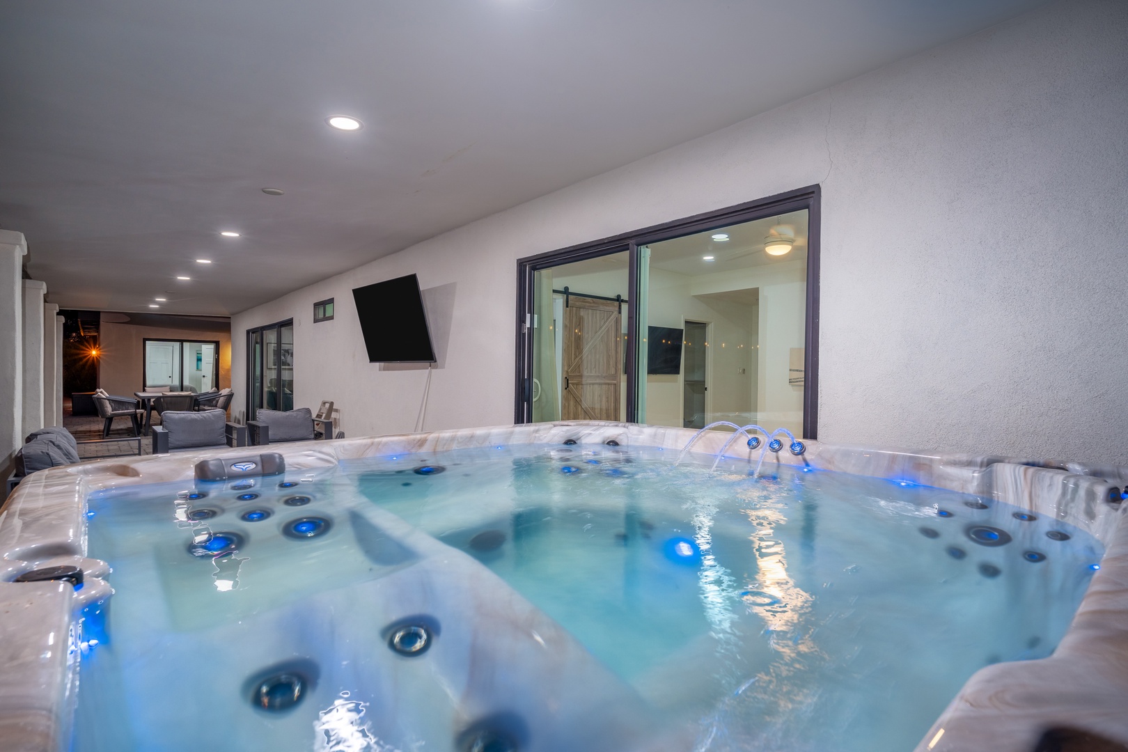 Slip into your private hot tub and let the warm, bubbling jets melt away stress as you gaze into the cozy living area beyond the glass doors.