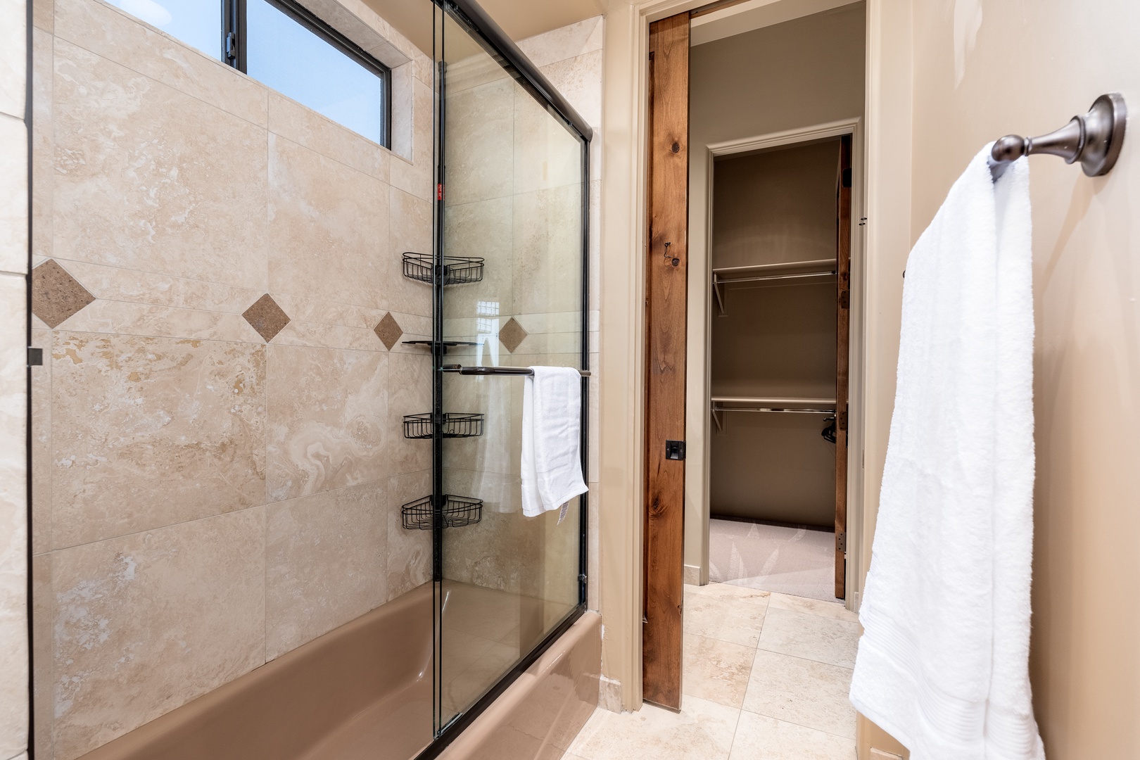 Step into your private spa retreat, where warm travertine tiles and a sleek glass-enclosed tub invite you to unwind after exploring. Fluffy towels and thoughtful touches await your arrival.