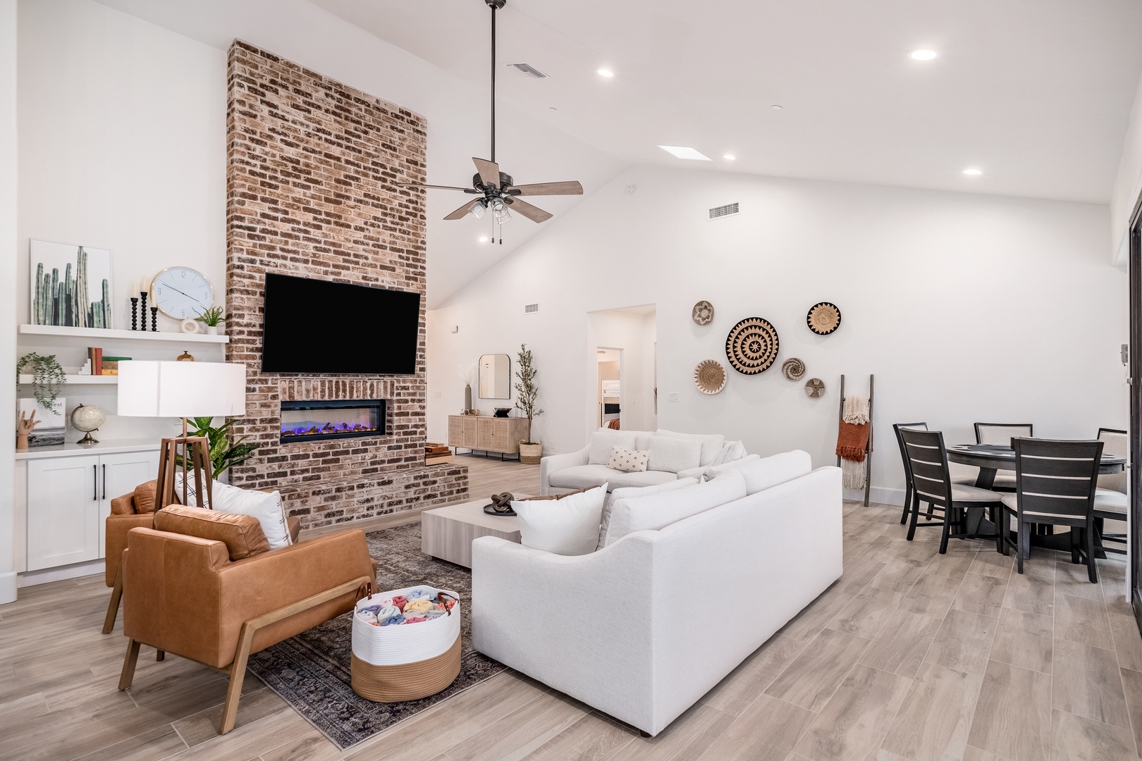 Step into your spacious haven with soaring ceilings, plush seating perfect for gathering, and a striking brick fireplace that anchors the room with warmth and character.