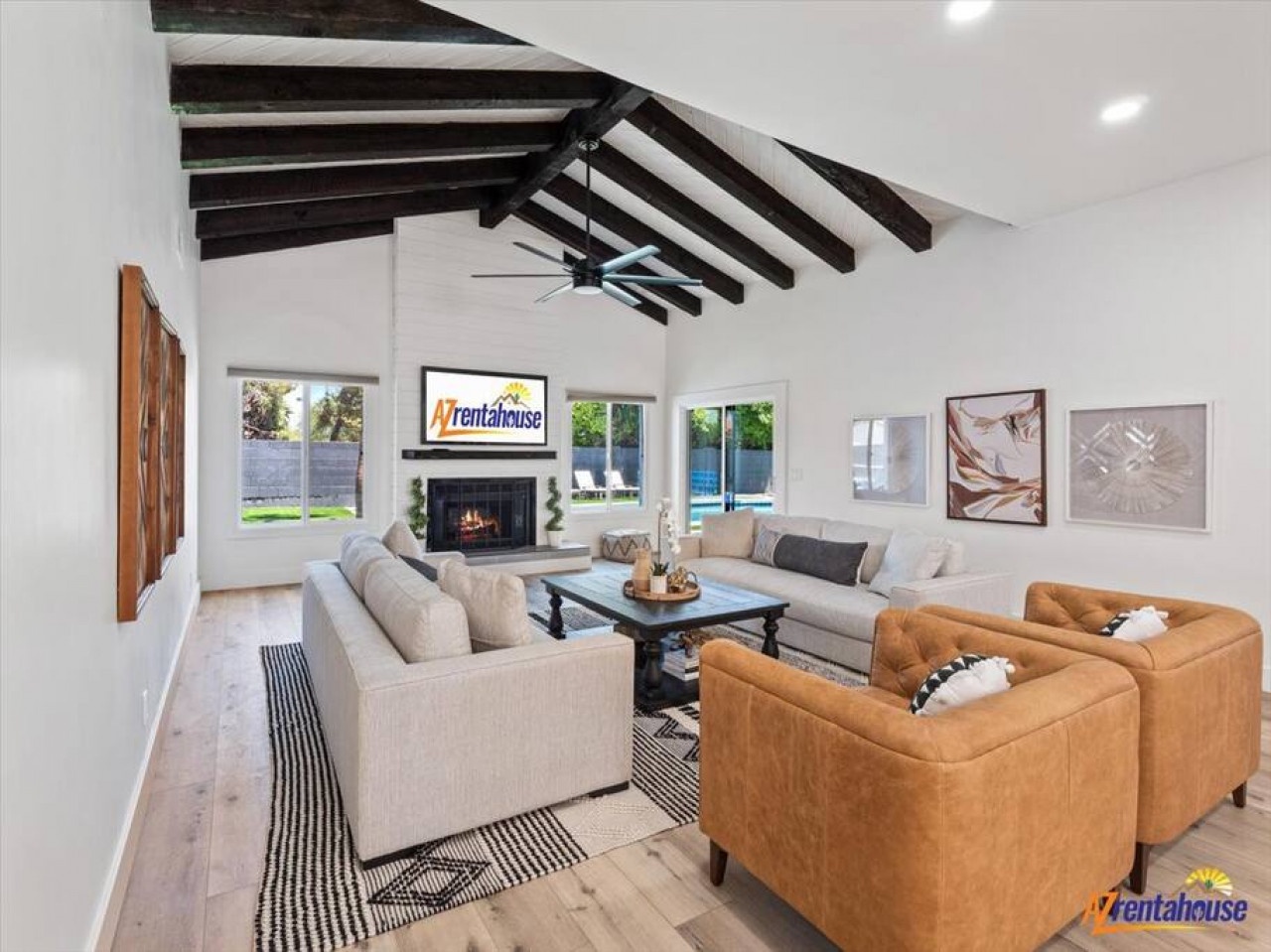Relax in your stylish living room with exposed beams, cozy fireplace, and comfortable seating overlooking the sparkling pool.