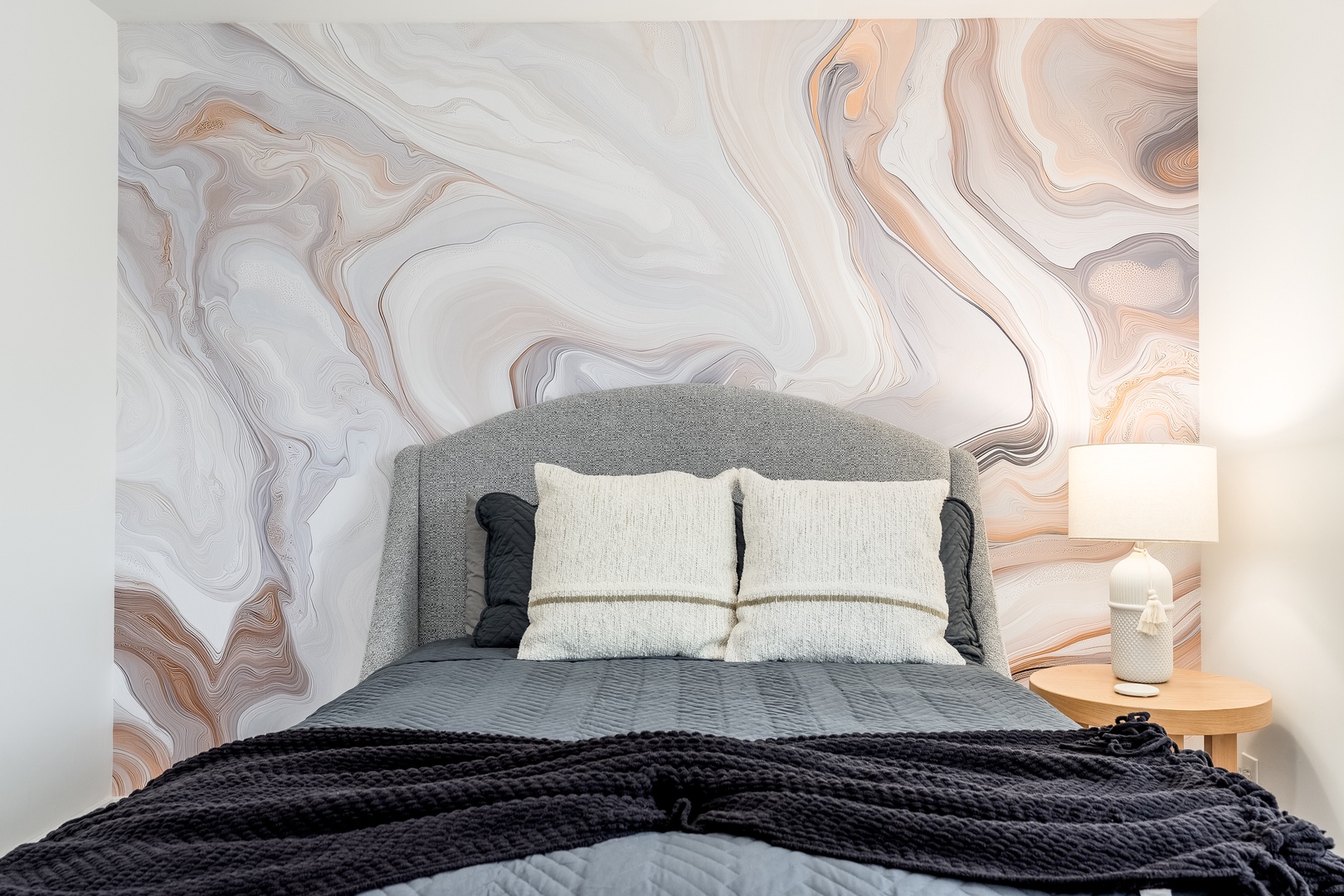 Sink into plush bedding and unwind beneath a dreamy marble accent wall. Your cozy nightstand lamp sets the perfect mood for a restful evening.