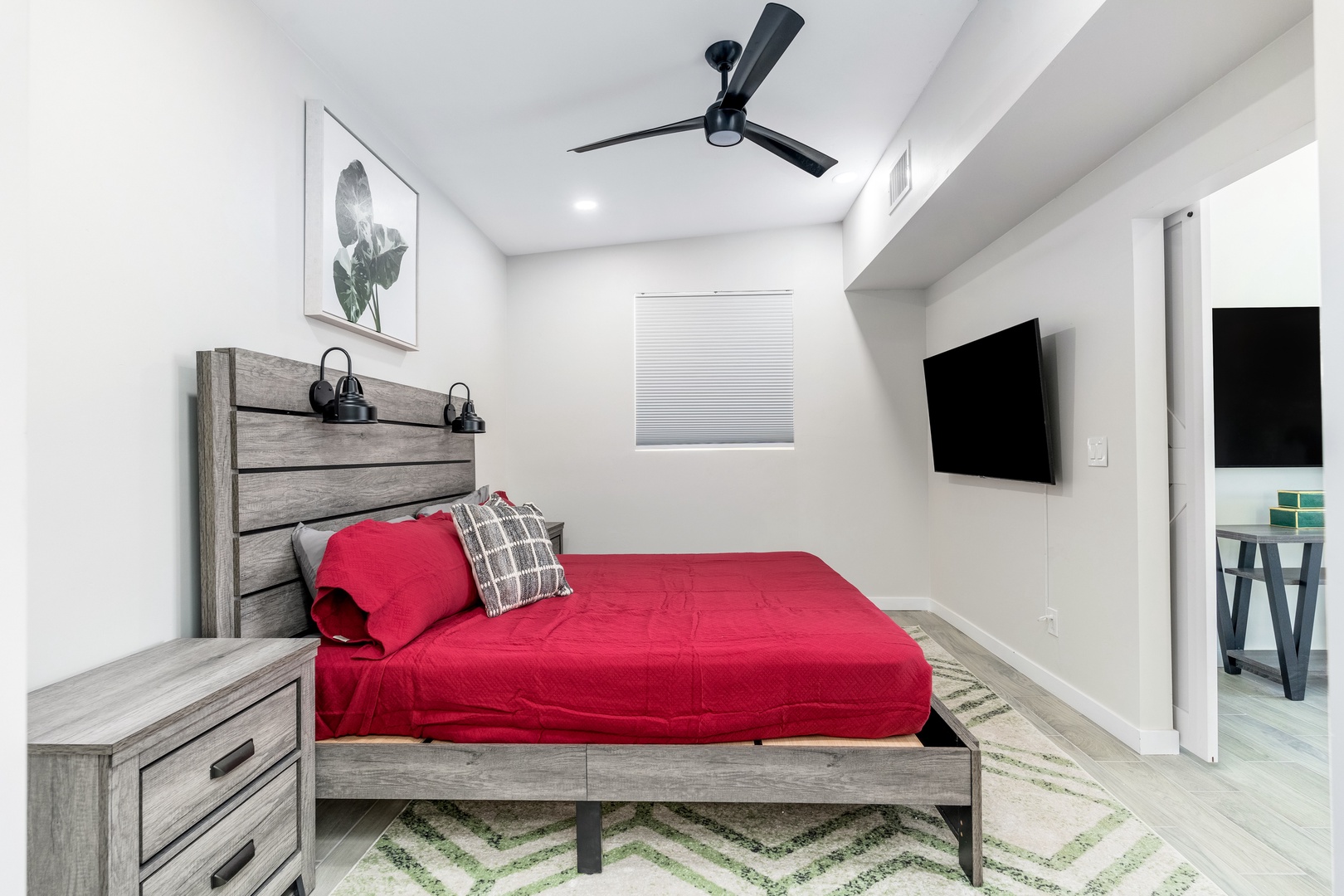 Sink into your cozy bed under the gentle ceiling fan, with a wall-mounted TV for your entertainment and warm bedside lighting for a relaxing evening in this cheerful retreat.