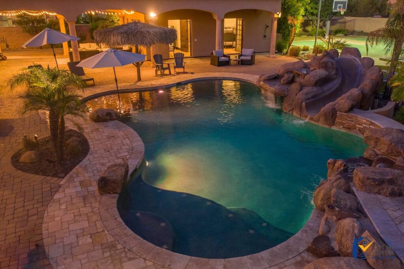 Dive into your private oasis with this stunning kidney-shaped pool featuring natural rock waterfalls, tiki bar, and tropical landscaping.