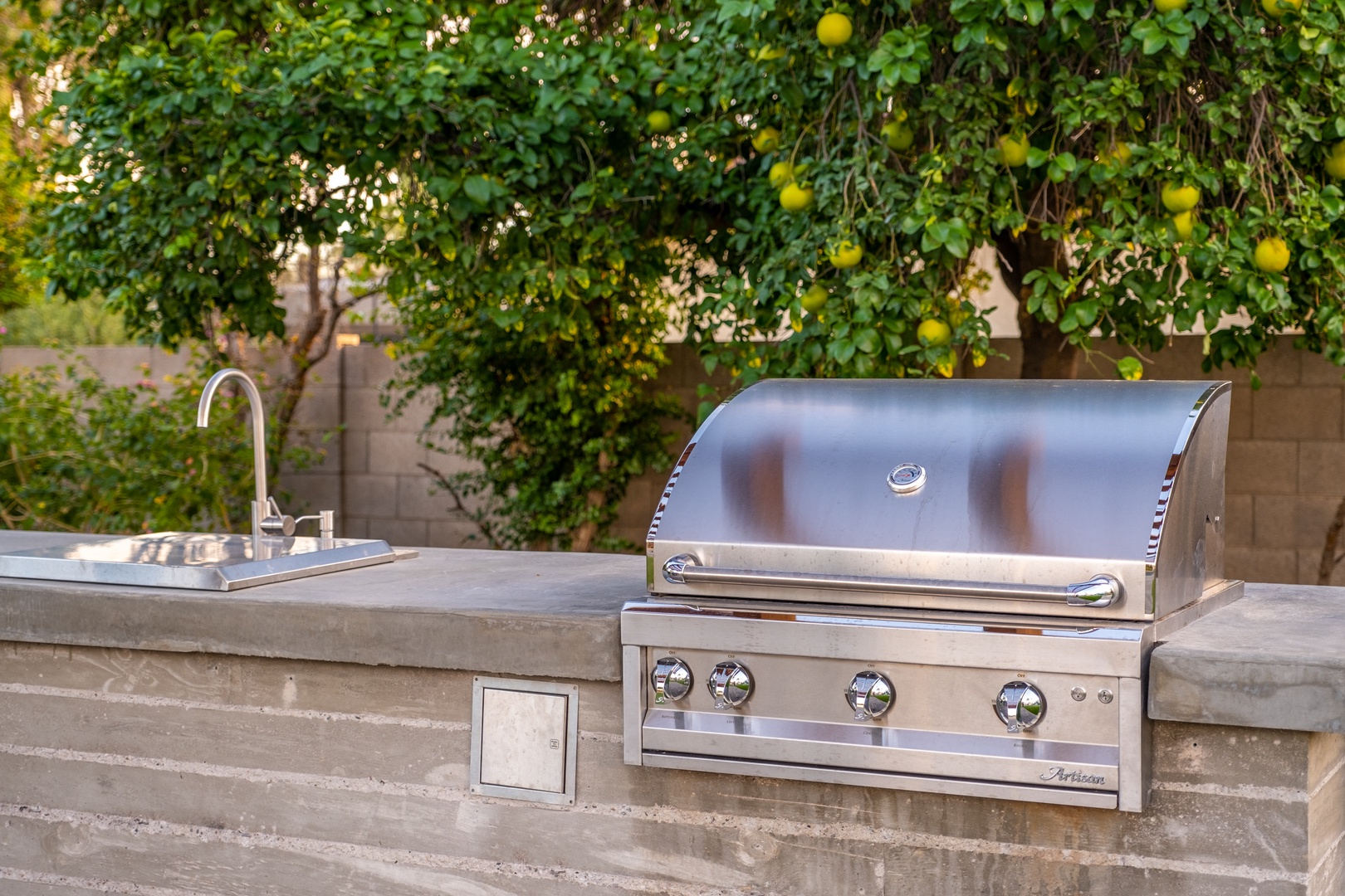 Your own outdoor kitchen awaits beneath the shade of a lush lemon tree, where a built-in stainless steel grill and sink make al fresco cooking effortless.