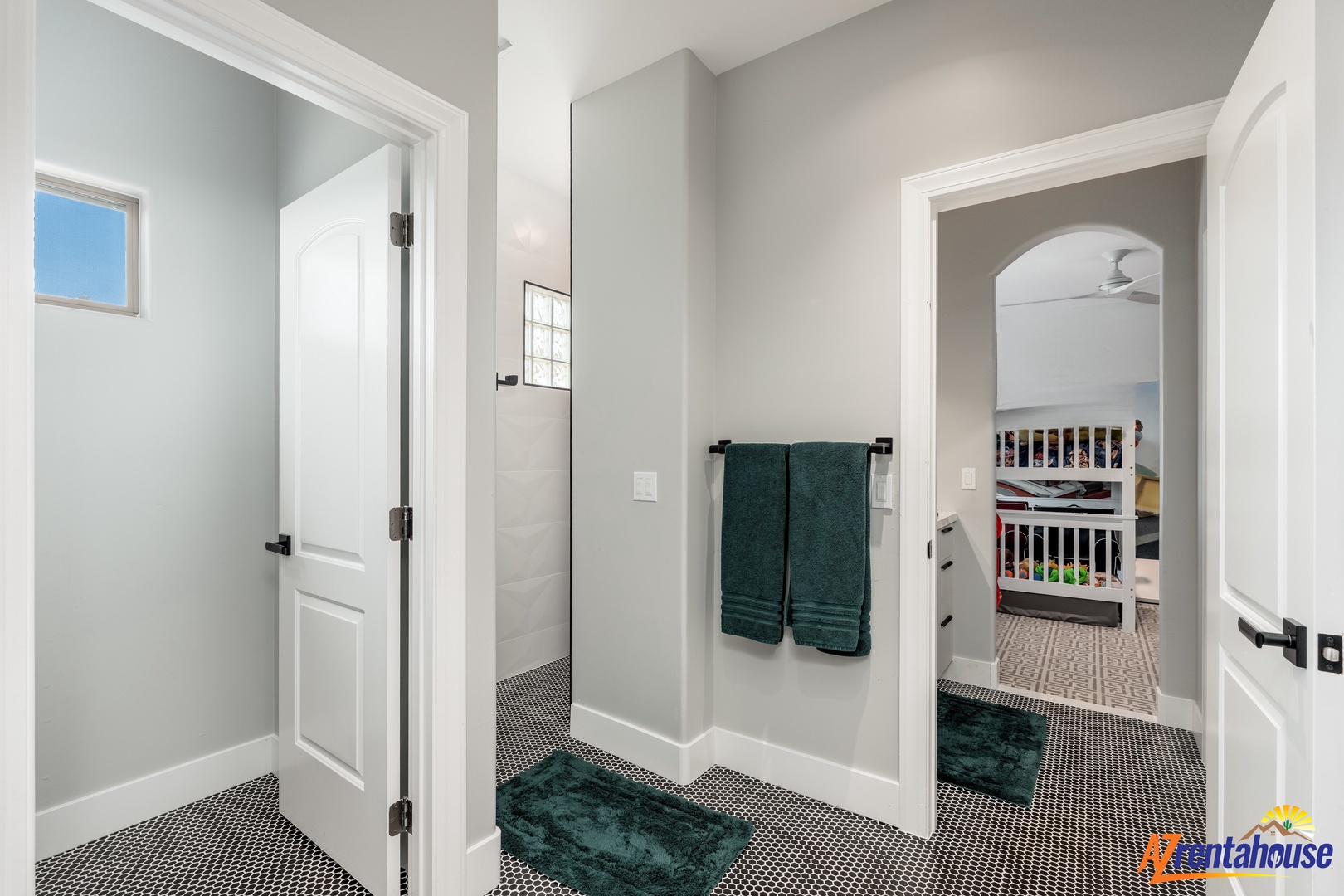 Your upstairs bathroom features a spacious layout with soft gray walls, classic black and white tile flooring, and rich teal accents that create a calming retreat.