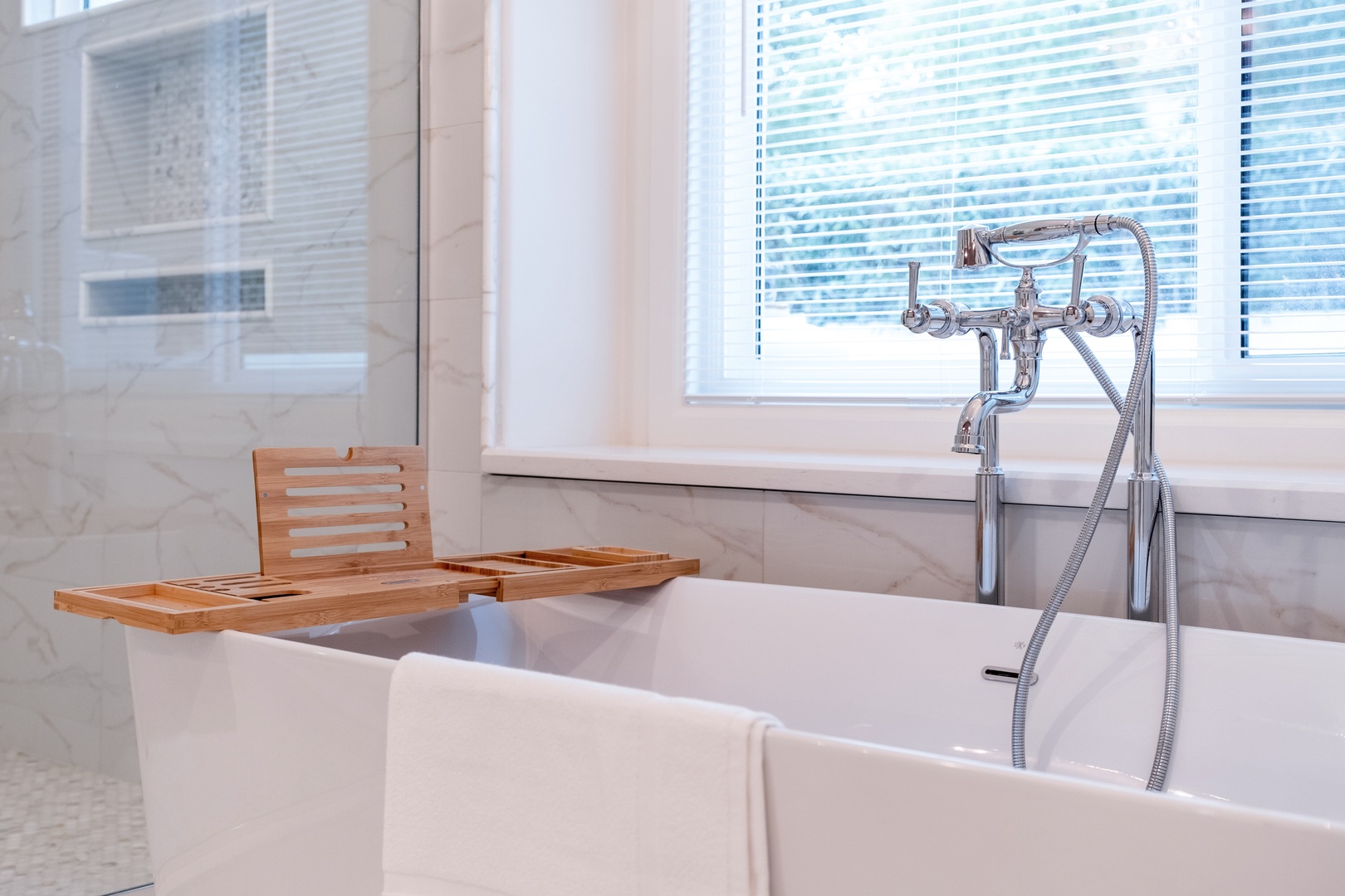 Picture yourself soaking in this elegant freestanding tub with a bamboo tray holding your favorite book and drink, while natural light filters through the window blinds creating your personal spa retreat.