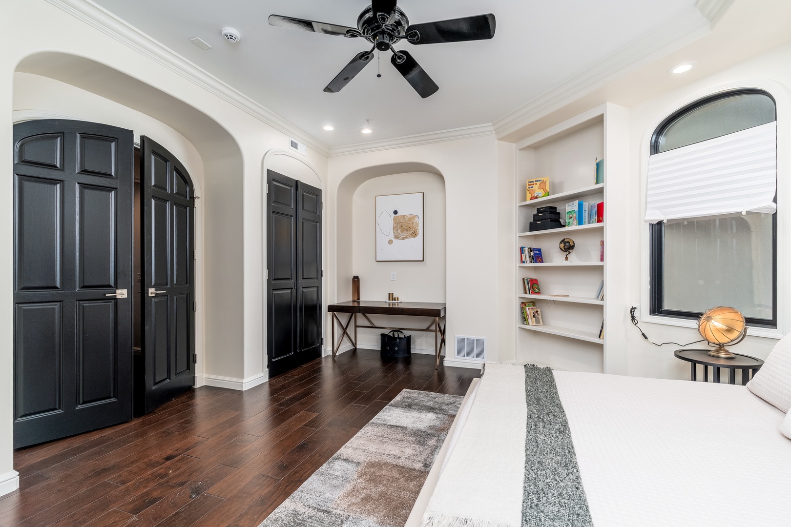 Step into this bright, inviting bedroom where rich dark wood floors contrast beautifully with crisp white walls. Built-in shelving keeps your favorite reads close, while ceiling fan ensures your ultimate comfort year-round.