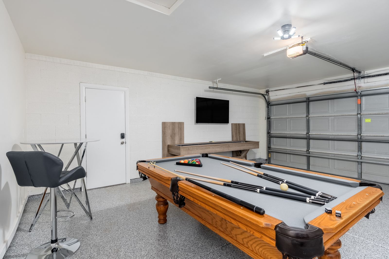 Challenge friends to a game of pool in your private game room, complete with a mounted TV and seating area for relaxed entertainment.