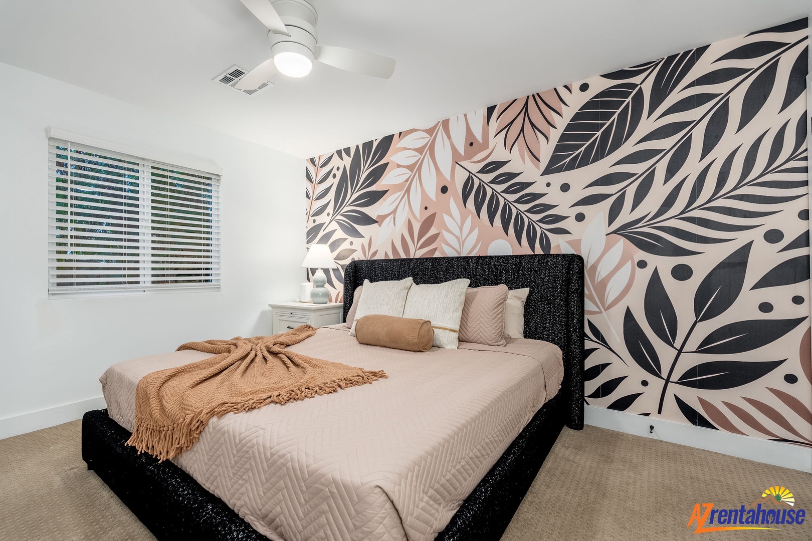 Your stylish bedroom features a striking botanical accent wall and plush bedding for restful nights.