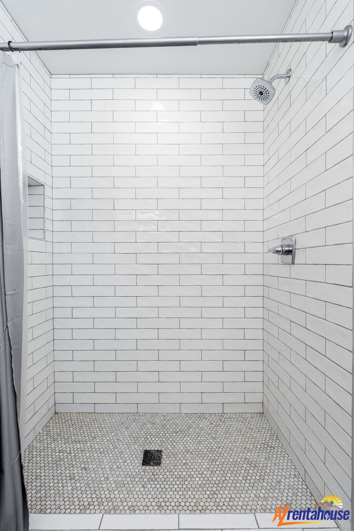 Step into your pristine white subway-tiled shower with rainfall head and spacious design for the perfect refreshing start to your day.