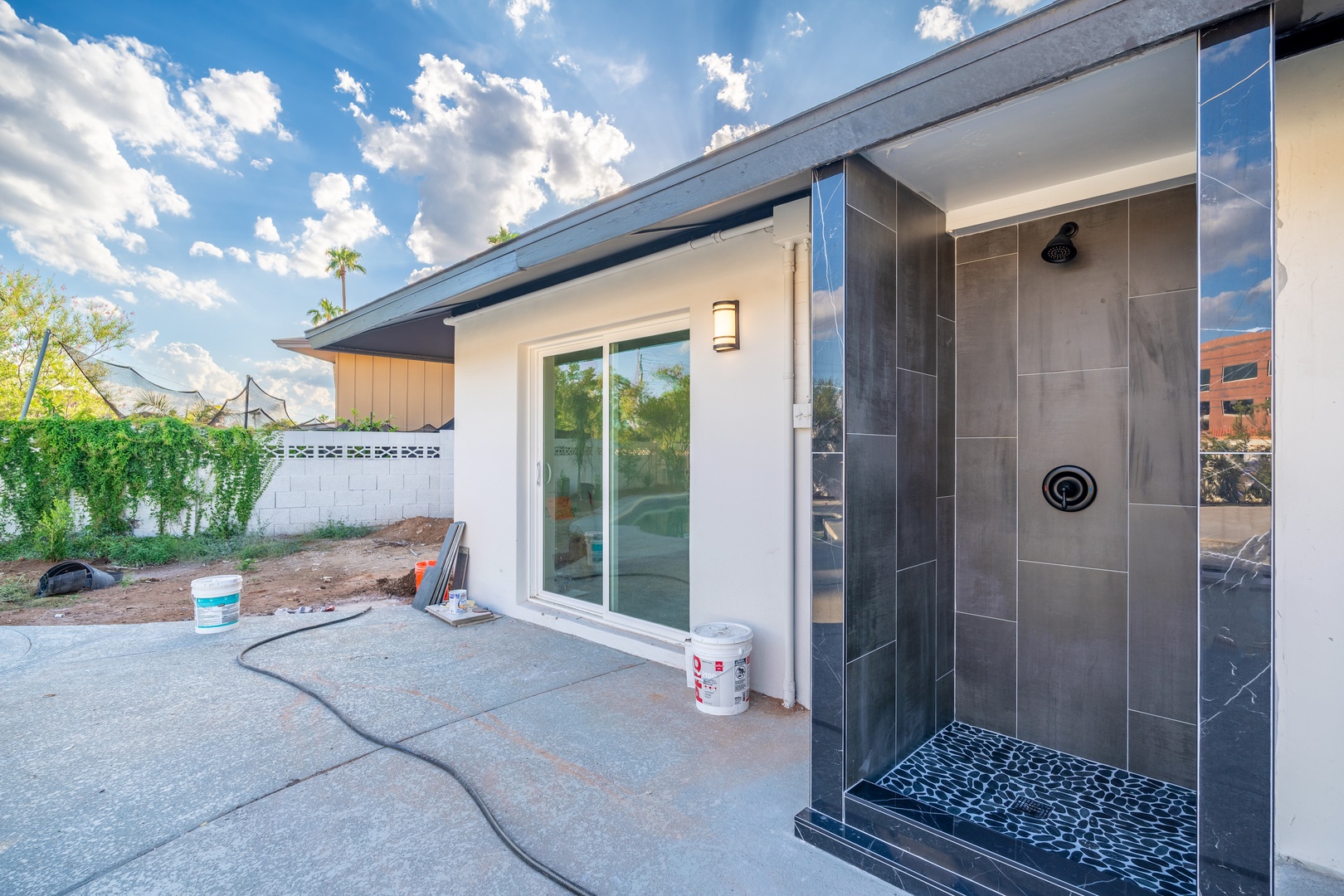 A sleek outdoor shower area with modern gray tile and pebble flooring, perfect for rinsing off after enjoying the sunny Arizona weather.