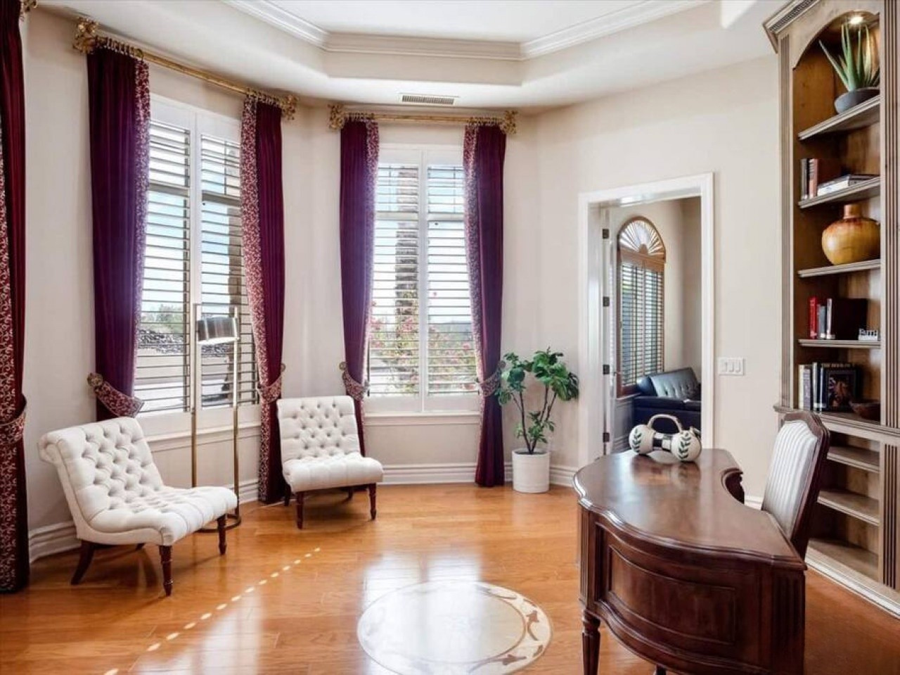 Your elegant home office features classic furnishings, warm wood tones, and natural light from oversized windows—a refined space to work or unwind in comfort and style.