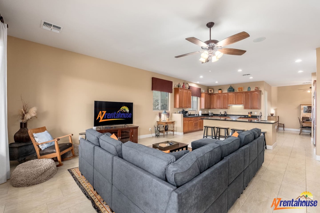 Unwind in your spacious open-concept living space with plush sectional seating, ceiling fan comfort, and seamless kitchen access for memorable evenings.