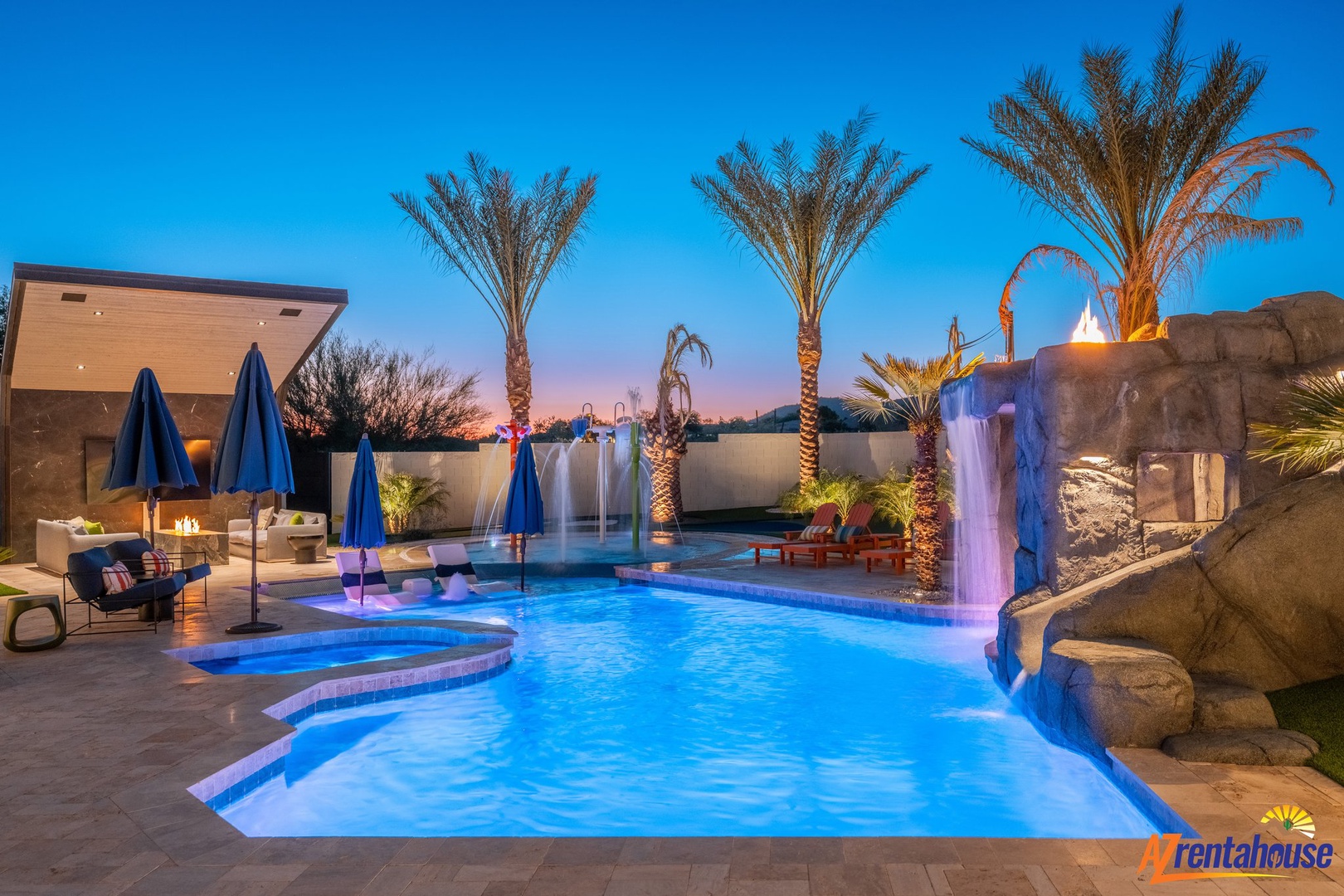 Stunning resort-style pool with waterfall features and tropical palms creates the perfect desert oasis backdrop.