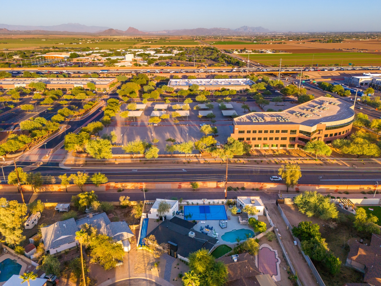 Aerial view of the property nestled in a scenic desert landscape, surrounded by mountains, agricultural fields, and neighboring commercial areas.