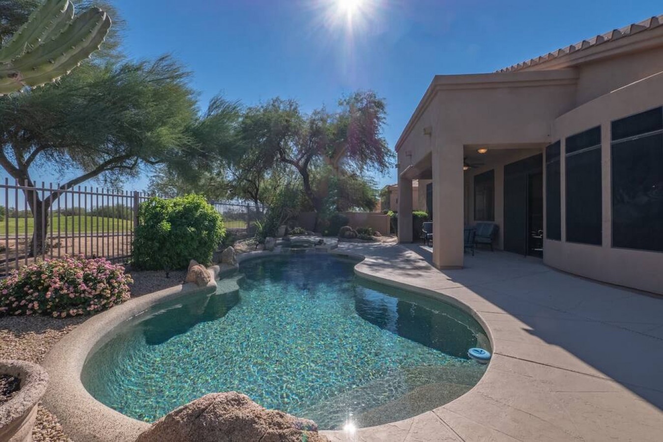 Desert oasis featuring a sparkling pool surrounded by native landscaping and mountain views.
