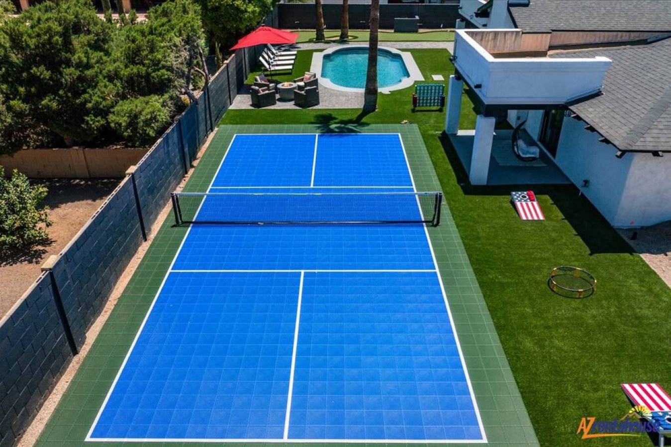 Aerial view of a private backyard featuring a full tennis court, pool, and outdoor amenities in a residential setting.