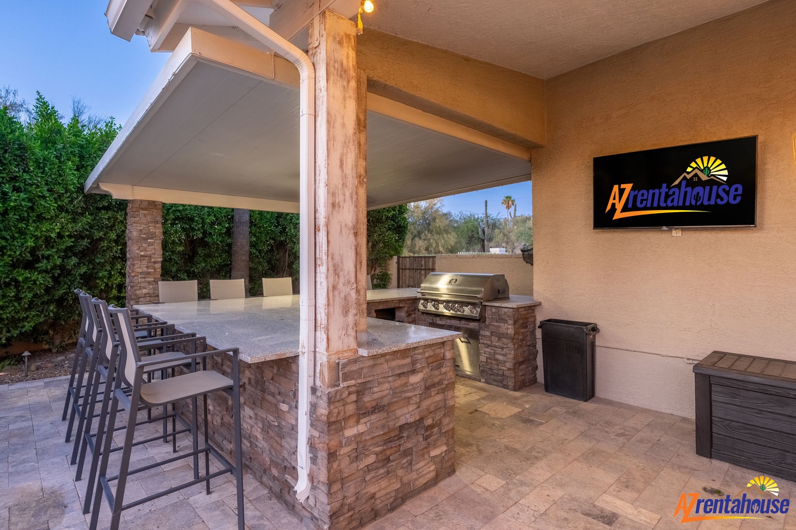 A covered outdoor kitchen with built-in grill and bar seating where you'll gather for meals under Arizona skies.