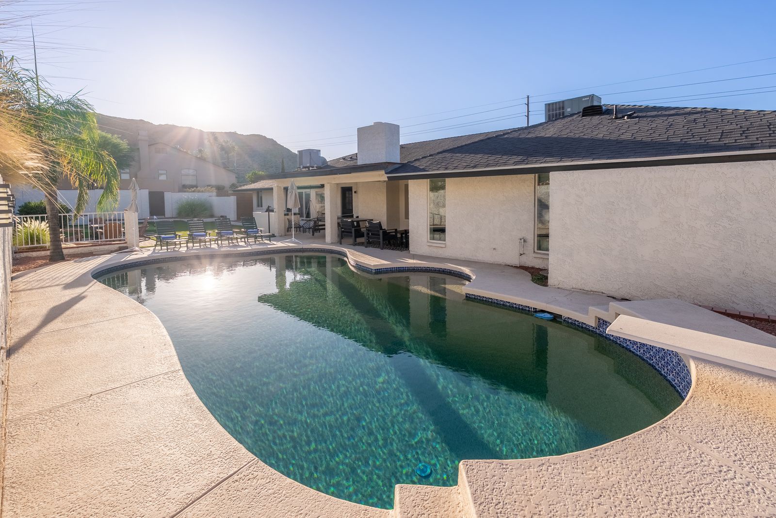 Private backyard oasis with sparkling pool, mountain backdrop, and ample patio space for relaxation and outdoor entertaining.