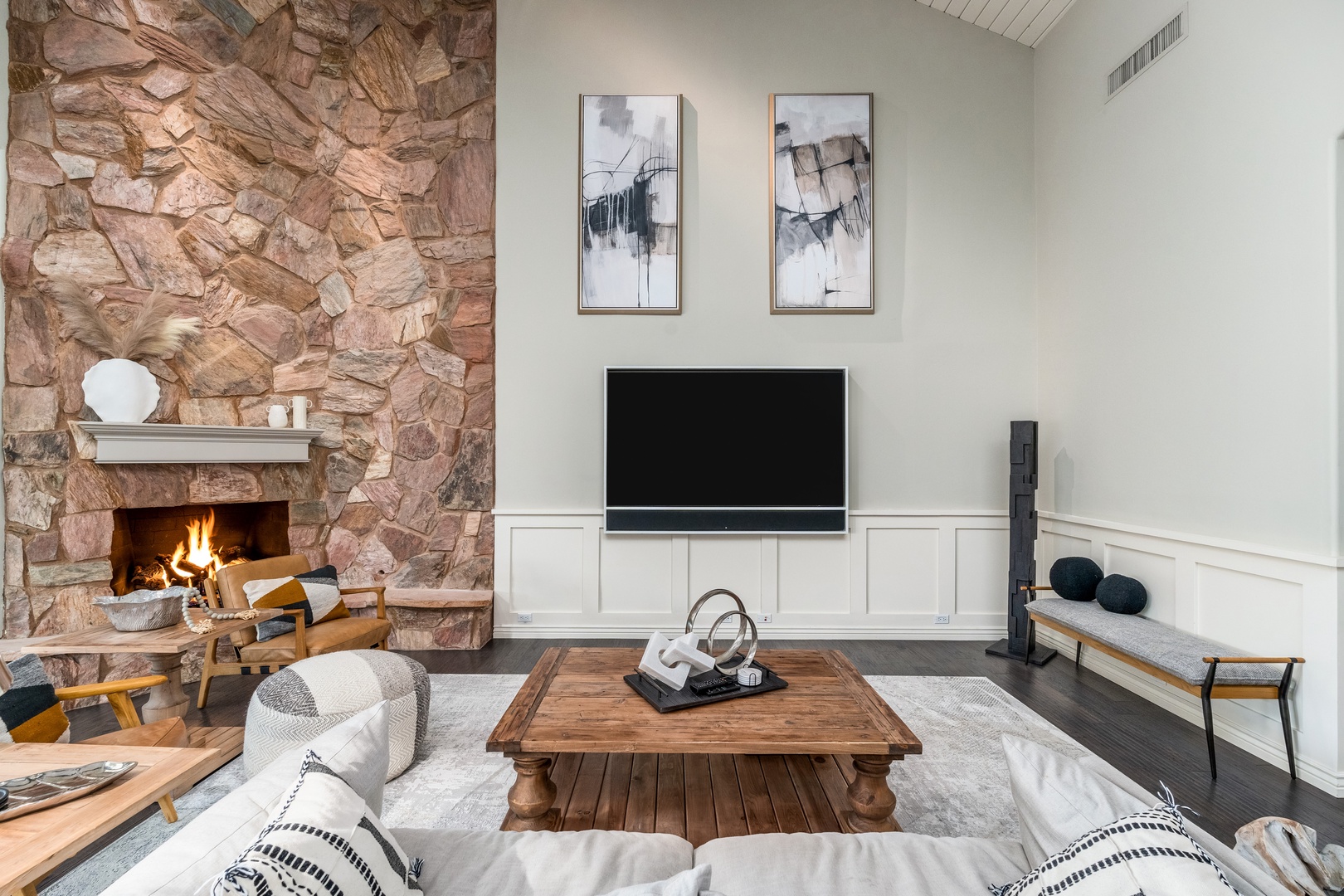 Gather around the rustic coffee table while the fire crackles in the stunning stone hearth. Modern art and cozy seating create your perfect retreat for relaxation.