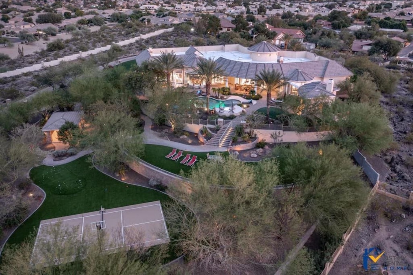 Stunning aerial view showcases this luxury desert estate with swimming pool, tennis court, and expansive landscaped grounds.