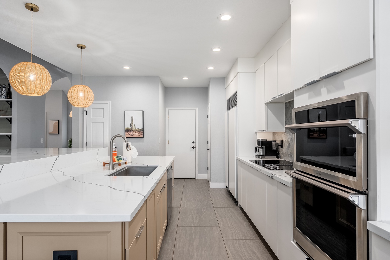 This bright modern kitchen features sleek countertops, stainless steel appliances, and warm pendant lighting—perfect for preparing your favorite meals during your stay.