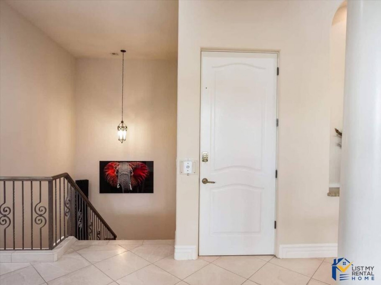 Step into your elegant entryway featuring polished tile floors, decorative staircase railings, and striking artwork that welcomes you home.
