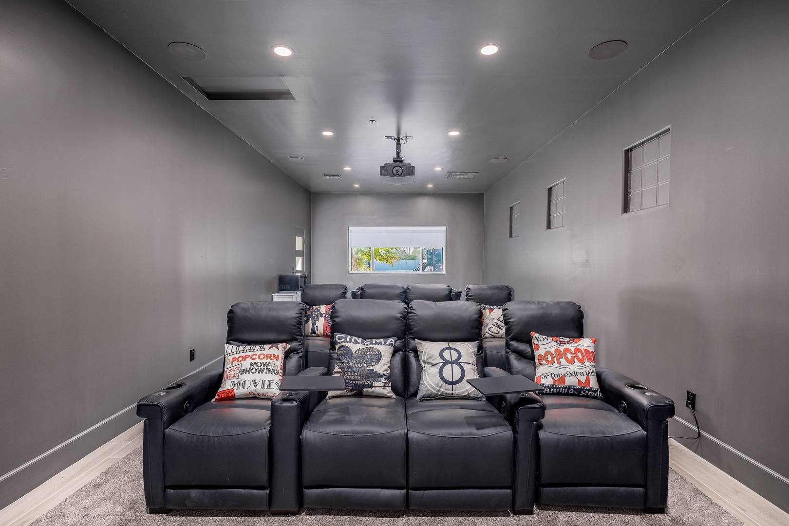 Sink into plush recliners with popcorn-themed pillows in your private home cinema, complete with a projector and surround sound for unforgettable movie nights.