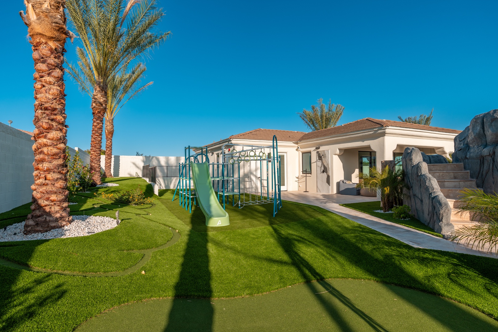 Expansive outdoor playground beneath swaying palms, perfect for family memories in this desert oasis setting.