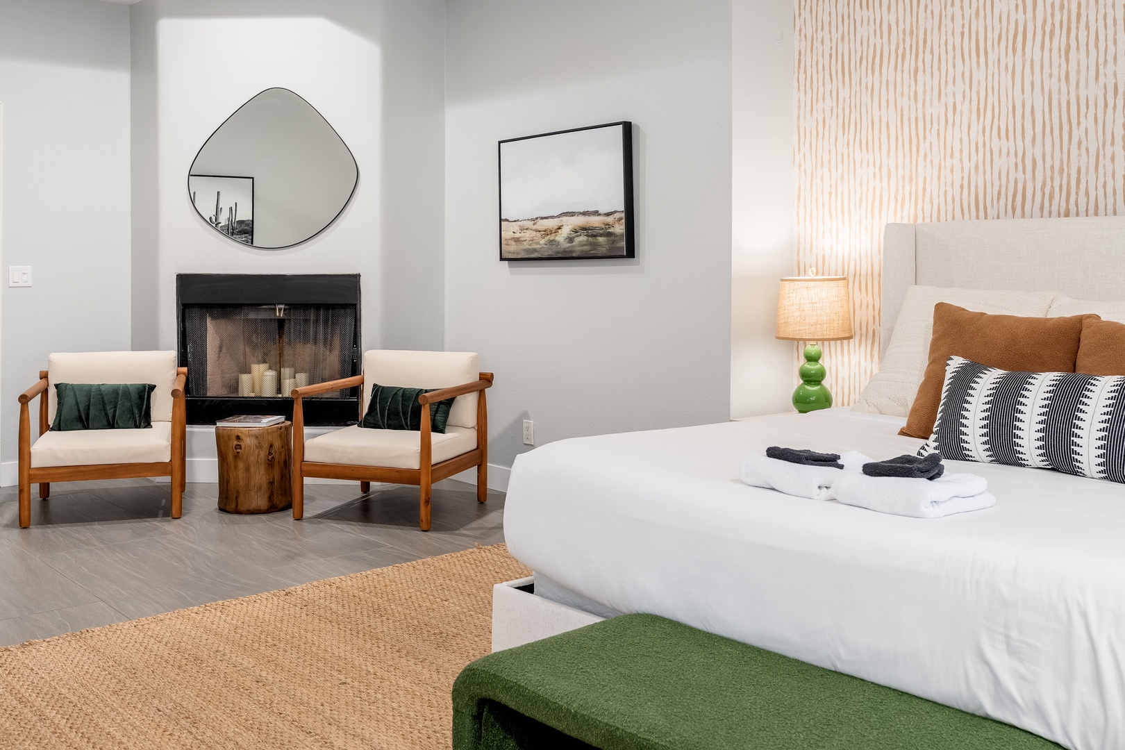Unwind in your serene bedroom where crisp linens meet a cozy fireplace and stylish mid-century seating—your perfect retreat after a day of exploring.